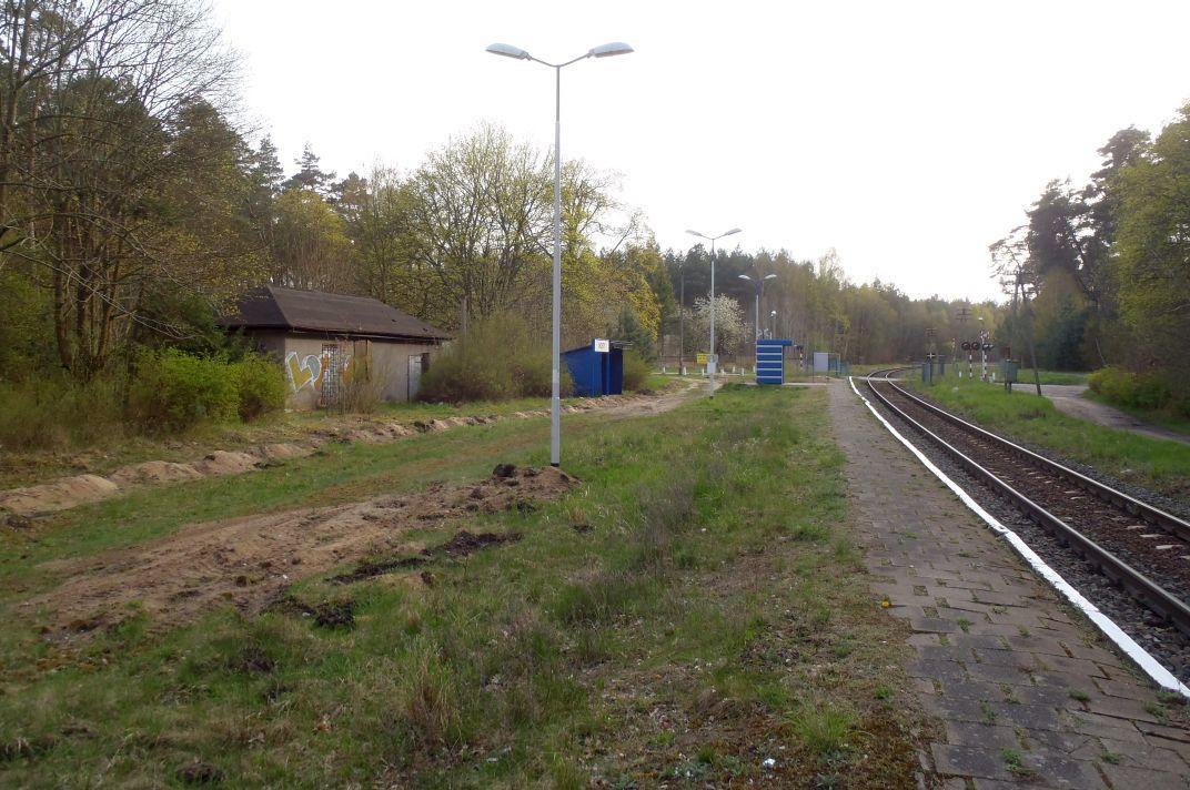 fot. octanq 
Mosty: widok ogólny w kierunku Goleniowa, od lewej: budynek stacyjny, słupy oświetleniowe, stara i nowa wiata przystankowa, a za prawym skrajem zdjęcia - jednostka wojskowa, do której dojeżdża się przez widoczny na zdjęciu przejazd kat. C. Obraz