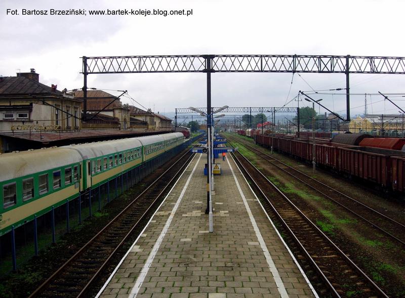 fot. Bartek Jaszczur 
PKP Nowy Sącz. Peron 2, z lewej peron 1 i budynek dworca. Zdjęcie wykonane z kładki nad torami. Widok na stację w kierunku północno-wschodnim, od strony wjazdów z Muszyny i Chabówki. Obraz