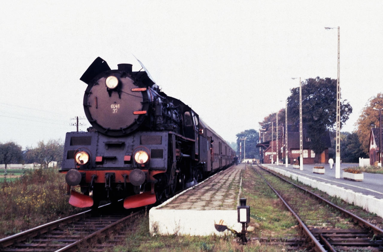 fot. Matthias Sitte 
Pociąg osobowy z Poznania do Wolsztyna z Ol49 na czele stoi przy peronie 2 stacji w Rakoniewicach. Widok w kierunku północno-wschodnim (Grodzisk Wielkopolski/Poznań). Obraz