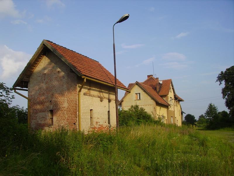 fot. andrzejkoza 
Zabudowania stacji. Na pierwszym planie toalety, w tle budynek dworca z magazynem towarowym. Widok od strony wjazdu z Pilszcza. Obraz