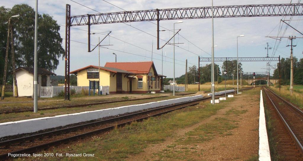 fot. Ryszard Grosz 
Widok na perony w kierunku Słupska. Z lewej budynek gospodarczy, magazyn towarowy i budynek dworca mieszczący nastawnię dysponującą. Obraz