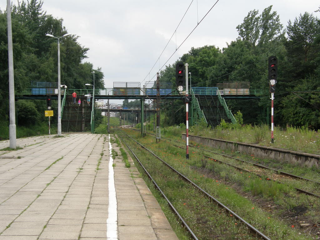 fot. Przemysław Więcek 
Peron pierwszy (po lewej) i drugi. Kładka zachodnia. W oddali wiadukt w ciągu ulicy Grota-Roweckiego. Widok w kierunku początku linii, stacji Tychy. 3,6 km. Obraz