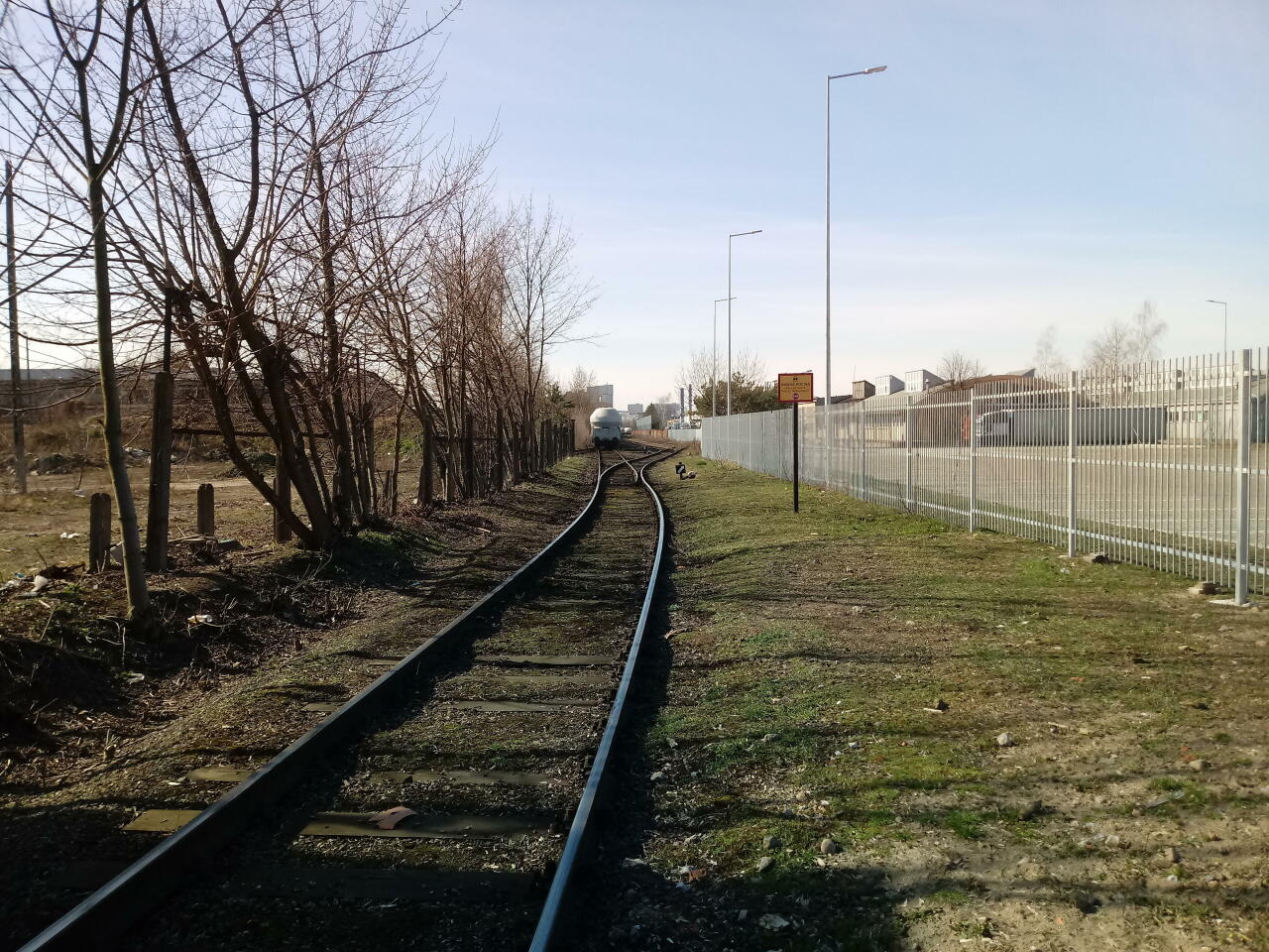 fot. Maciej Knychała 
Widok w kierunku zachodnim. Zdjęcie wykonane w odległości ok. 100 m od ul. Gdyńskiej (Poznań). Tor przebiega pomiędzy ul. Bałtycką a budynkiem z napisem EXIDE. Obraz
