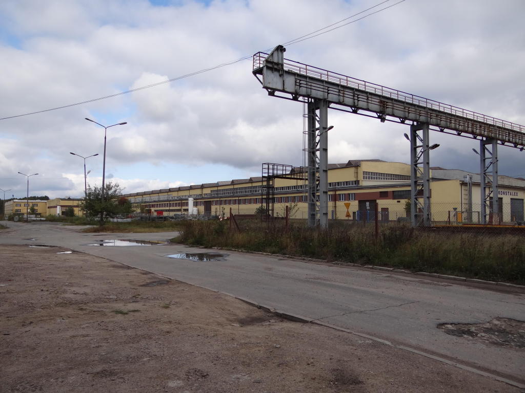 fot. Przemysław Więcek 
Bocznica zakładów metalowych. Widoczna główna hala o powierzchni zabudowy ok. 6500 mkw. (elewacja zachodnia). Prowadziły do niej tory z dwóch krańców. Po prawej plac składowy z suwnicami pomostowymi o udźwigu 20 t i rozpiętości 30 m i ciągiem technologicznym torów kolejowych. Widok w kierunku stacji Radomsko. 3,5 km. Obraz