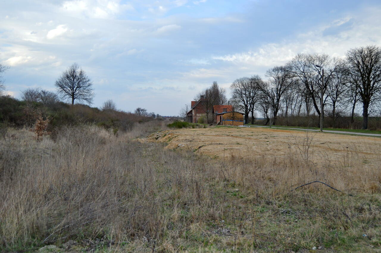 fot. Tomasz 
Laski-Smardze. Widok na dawną stację od strony Namysłowa. W oddali widoczny budynek toalet oraz budynek dworca. Obraz