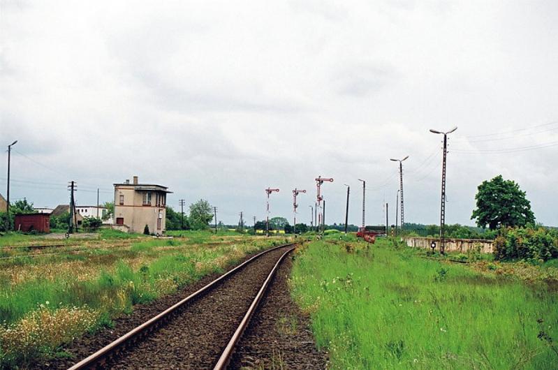 fot. Włodzimierz  Ziomek 
Wyjazd w kierunku Szczecinka. Po prawej stronie - mocno zarośnięta i dawno nie używana, grupa torów prowadzących do rampy rozładunkowej, od strony budynku dworca. Za budynkiem nastawni, widoczny przejazd z drogą Człuchów - Debrzno. Obraz