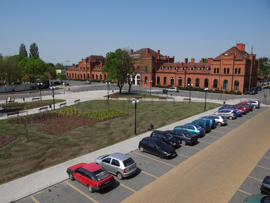 fot. Przemysław Więcek 
Plac dworcowy. Budynek dworcowy od strony placu dworcowego. W lewo Koluszki i Łowicz, w prawo Góra Kalwaria i Żyrardów. 65,9 km / 0,0 km. Obraz