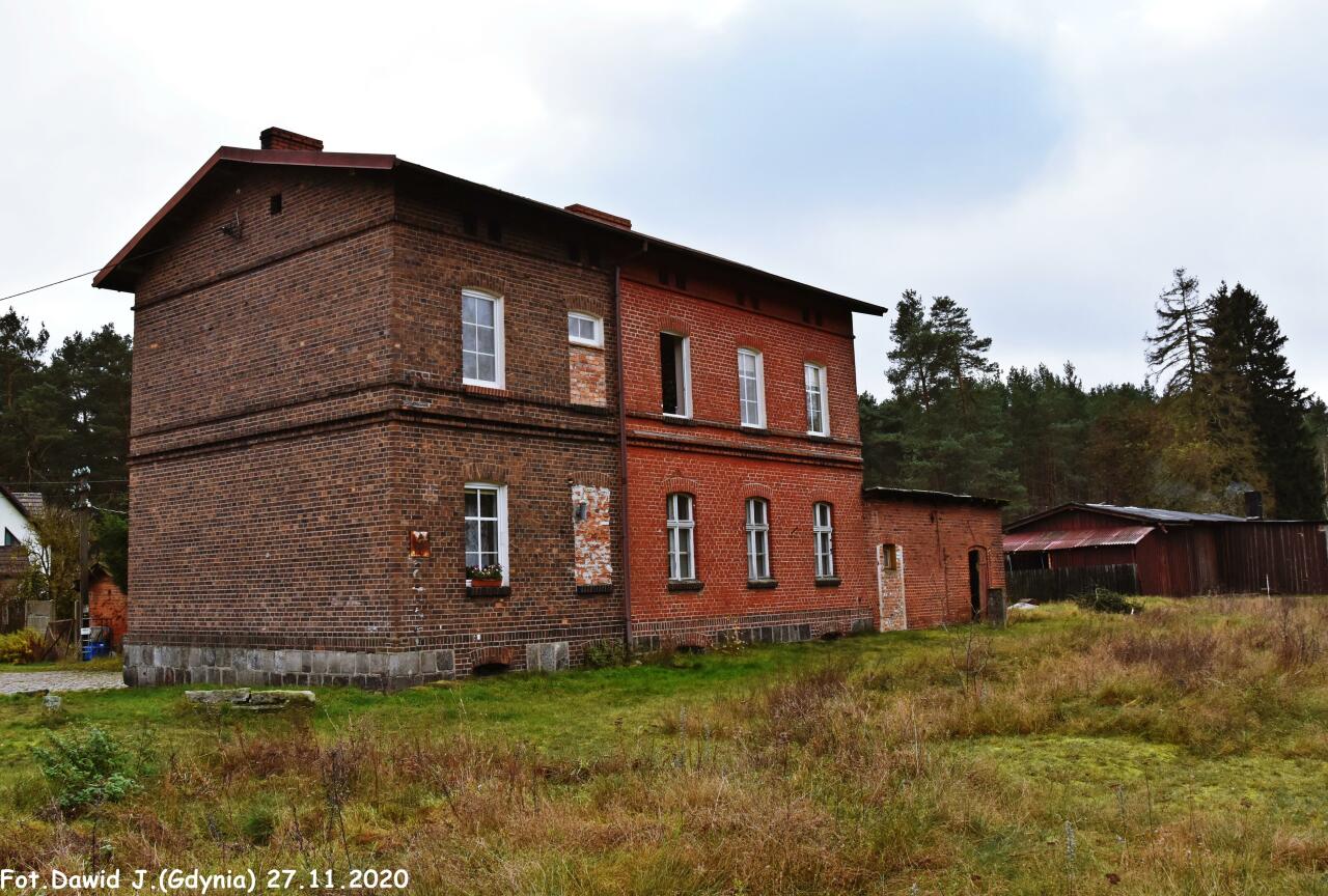 fot. Dawid Jastrzębski 
Kolejowy budynek mieszkalny z przyległą częścią z pomieszczeniami WC i budynek dworcowy. Obiekty widoczne od strony torów. Widok w kierunku Kalisza Pomorskiego i Stargardu. Obraz