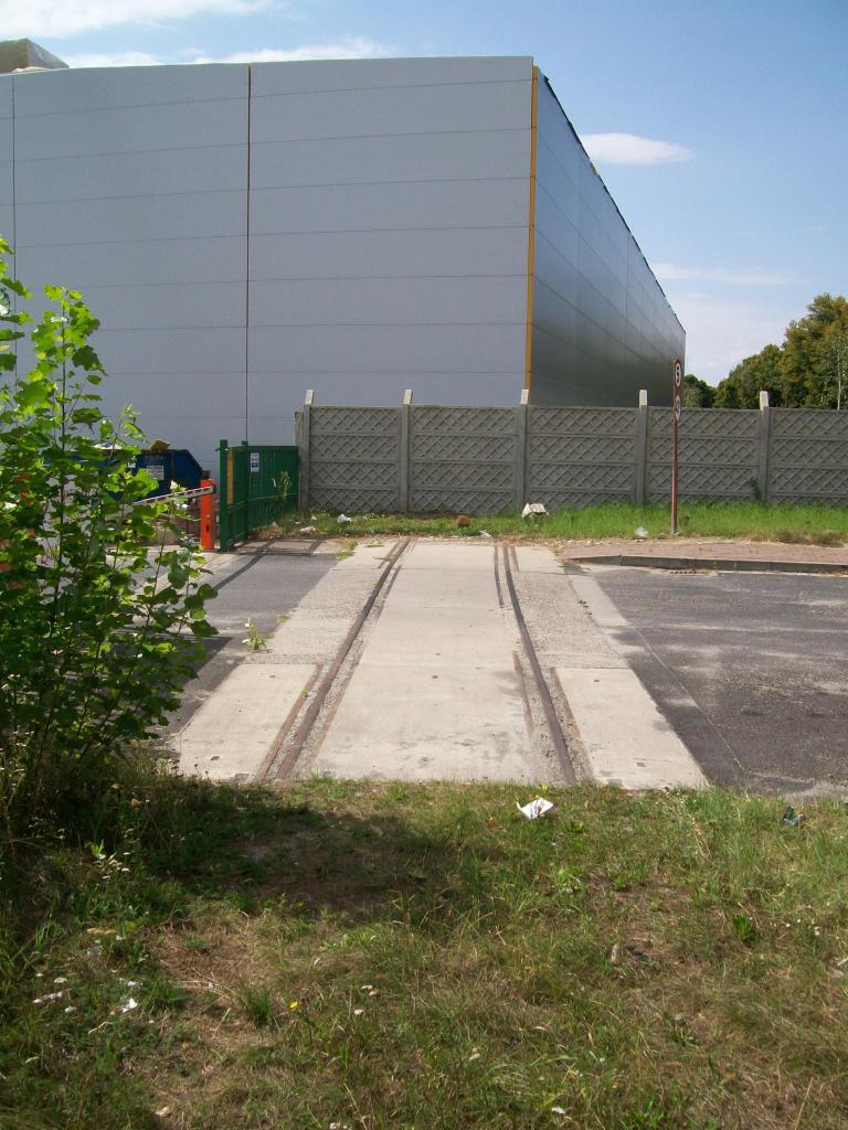 fot. wasiukibic 
Oławska Kolej Portowa. Tu jeszcze nie zdążono wyrwać nawierzchni przejazdu na drodze dojazdowej do zakładu papierniczego. Nowa hala fabryczna została posadowiona na starotorzu. Widok w kierunku stacji Oława. O ile dobrze sięgam pamięcią, gdy władze Oławy szukały inwestorów dla tego terenu w latach 90. jako jeden z atutów podawały obecność bocznicy kolejowej... Obraz