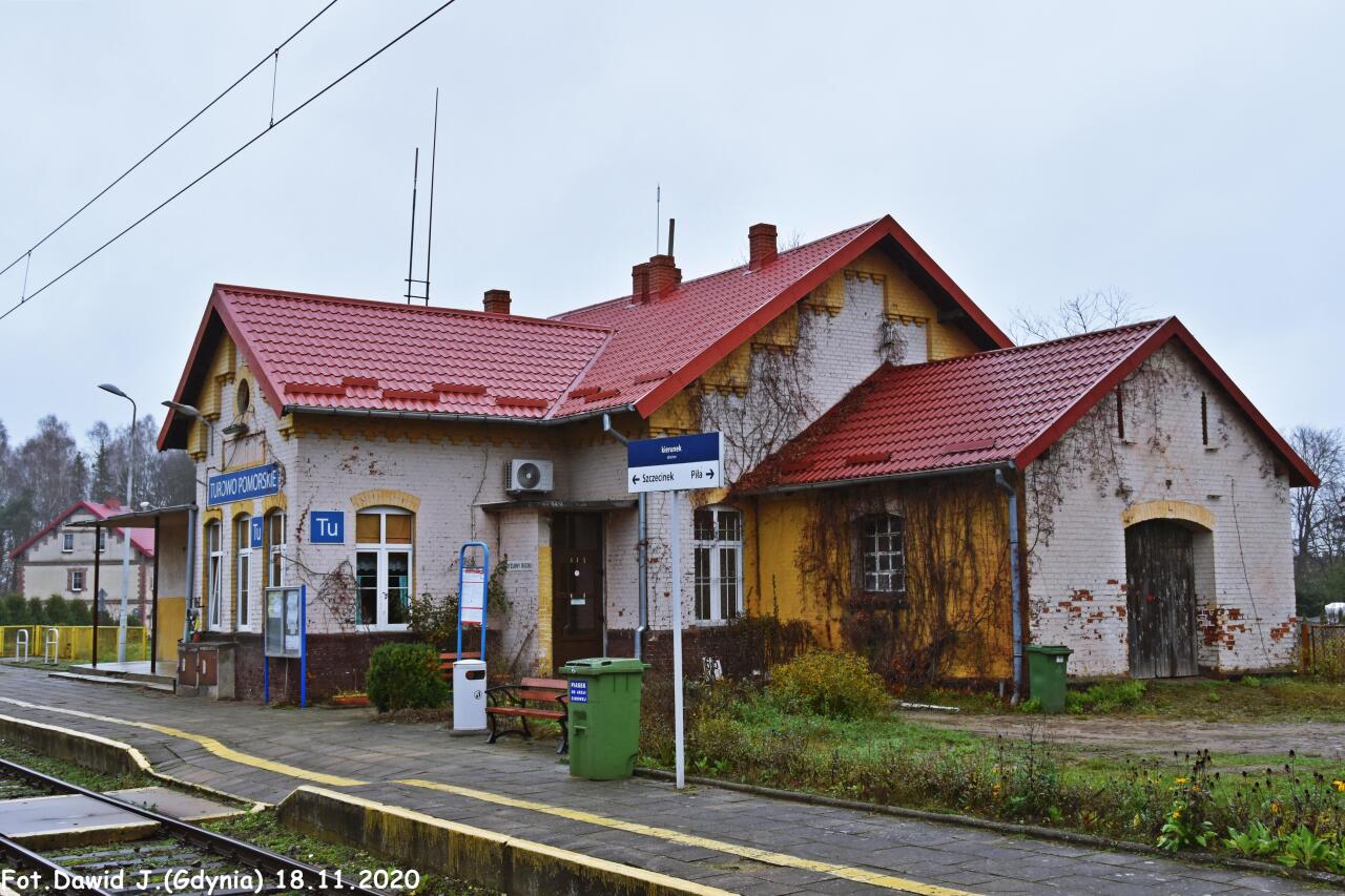 fot. Dawid Jastrzębski 
Kolejowy budynek mieszkalny nr 1 i budynek dworcowy. W budynku dworcowym znajduje się nastawnia "Tu". Obiekty widoczne od strony torów. Widok w kierunku Szczecinka. Obraz