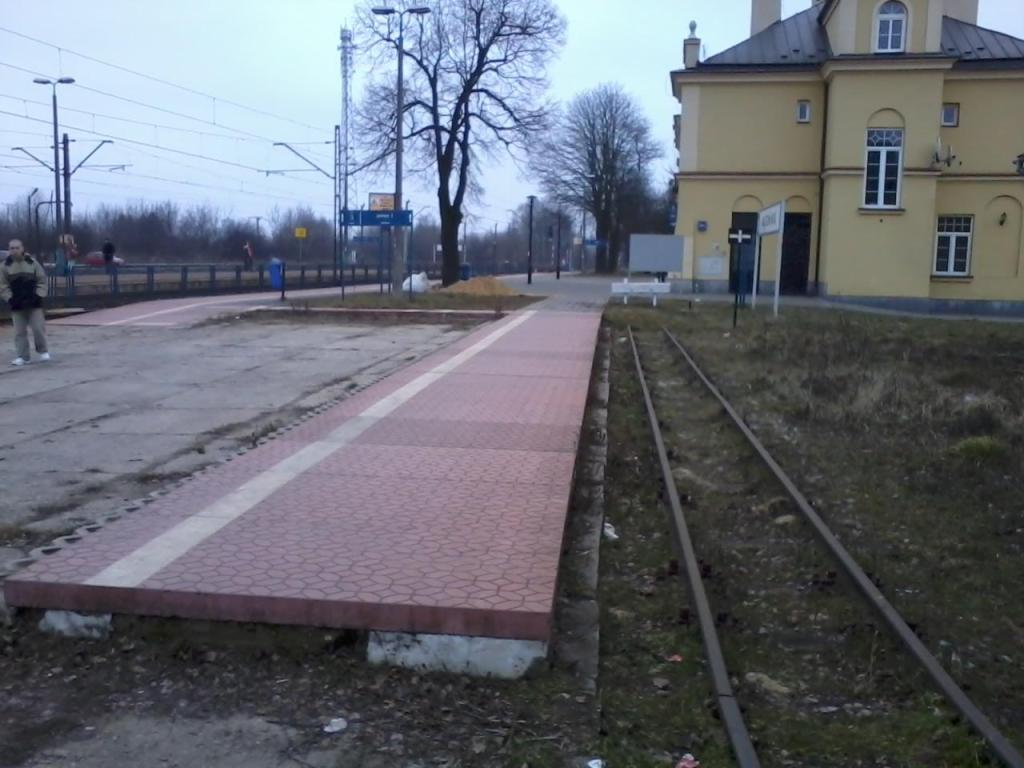 fot. Adrian Chromik 
Mały peronik stacyjki Nałęczów Wąskotorowy oraz budynek normalnotorowego dworca PKP Nałęczów od strony zachodniej. Widok w kierunku Czesławic i Lublina. Obraz